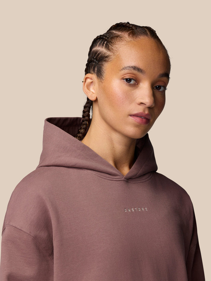 Close-up of a man wearing Adapt Lifestyle Hoodie in mauve with hood down and Castore logo on the chest.