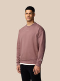 Male model wearing mauve Adapt Lifestyle Sweatshirt with crew neck and oversized relaxed fit; embroidered logo on chest and Castore wings on left sleeve.