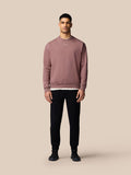 Male model wearing mauve Adapt Lifestyle Sweatshirt with oversized fit, paired with black joggers and white sneakers.