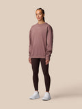 Female model wearing mauve Adapt Lifestyle Sweatshirt with oversized silhouette and dark leggings.