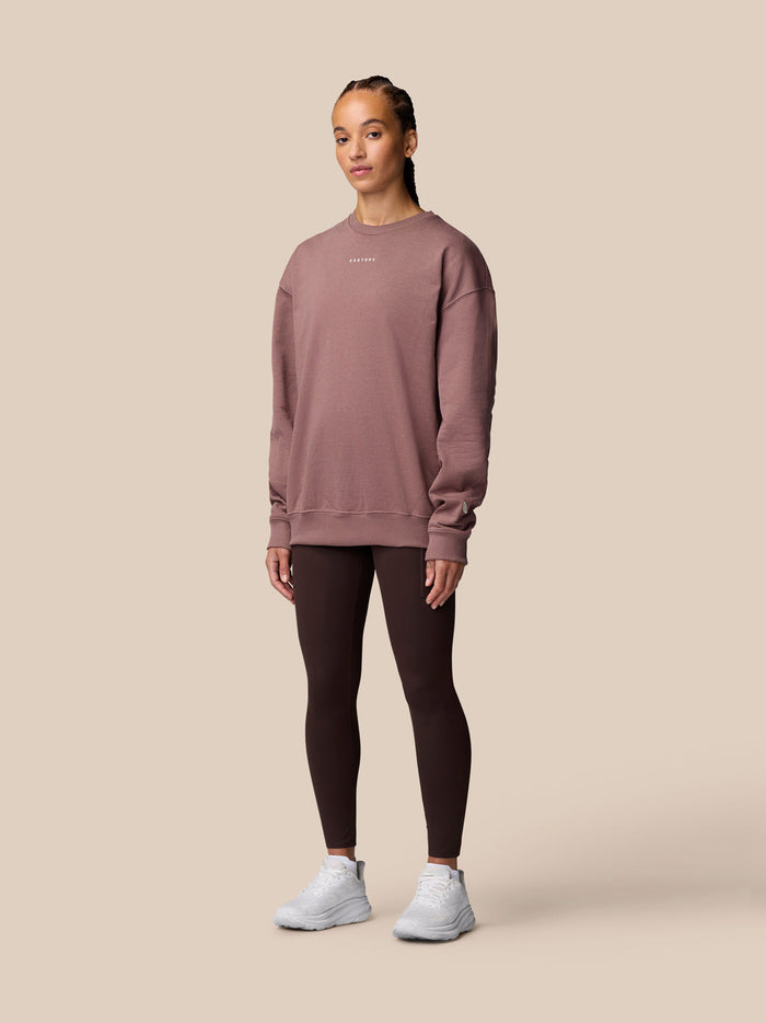 Female model wearing mauve Adapt Lifestyle Sweatshirt with oversized silhouette and dark leggings.