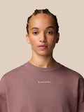 Female model wearing mauve Adapt Lifestyle Sweatshirt with oversized relaxed fit and front Castore logo