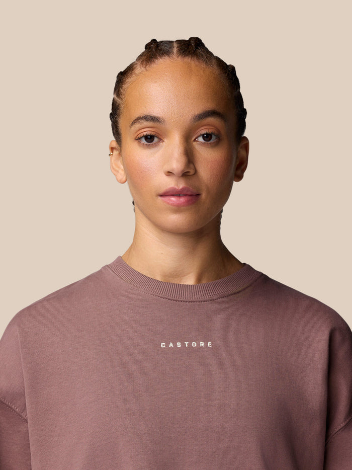 Female model wearing mauve Adapt Lifestyle Sweatshirt with oversized relaxed fit and front Castore logo