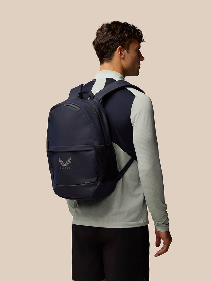 Back view of a person wearing navy Active Small Backpack with logo on the front pocket.