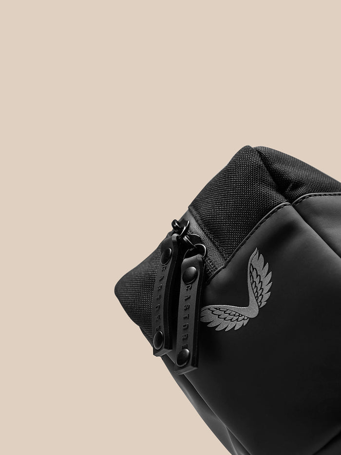 Close-up of the wash bag zipper with a branded pull and visible logo on black fabric.