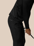 Close up of black golf trousers with Castore logo on the hip, with a golf club in the model's hand.