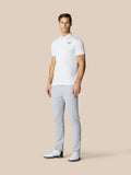Full body shot of a man in a white polo and light grey Golf Club Trousers, showcasing modern golf attire