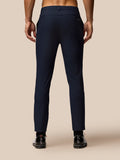 Back view of navy golf trousers on a model with branding at the back pocket and long leg length.