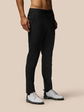 Male model wearing black Golf Club Trousers with open side pockets and welt back pocket, paired with light golf shoes.