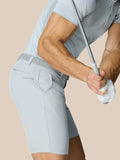 Side view of model in light grey golf shorts with a woven belt and branding on the back pocket while gripping a golf club