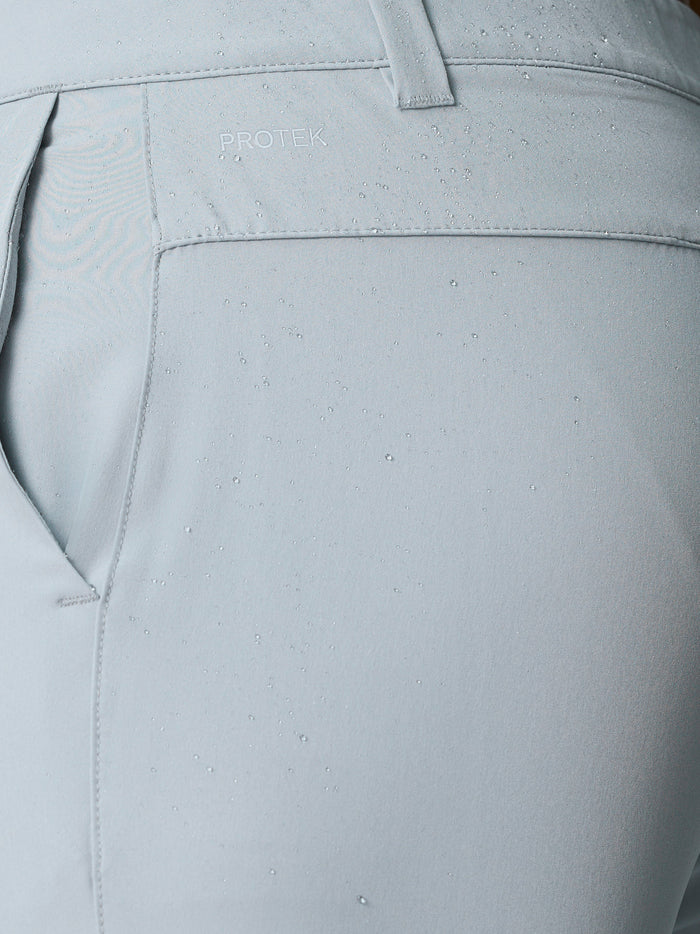 Close up of light grey golf shorts with ProTek label and water droplets on the fabric