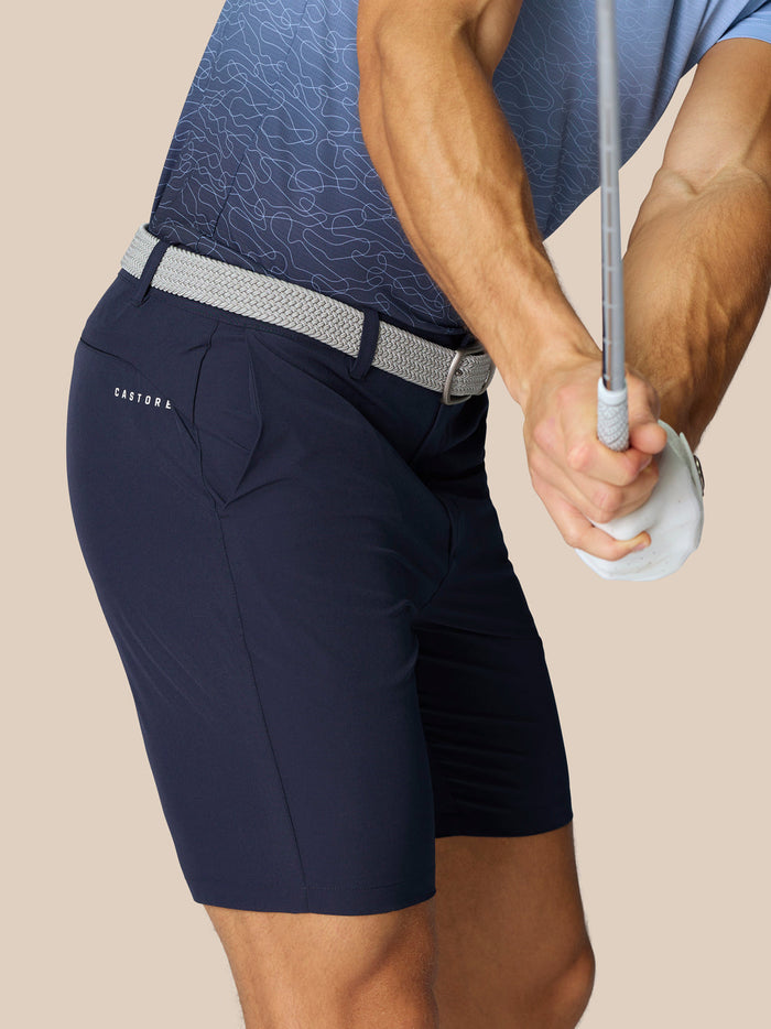 Side view of navy Castore Golf Club shorts with a woven belt; Castore branding on the thigh and ProTek at the waistband.