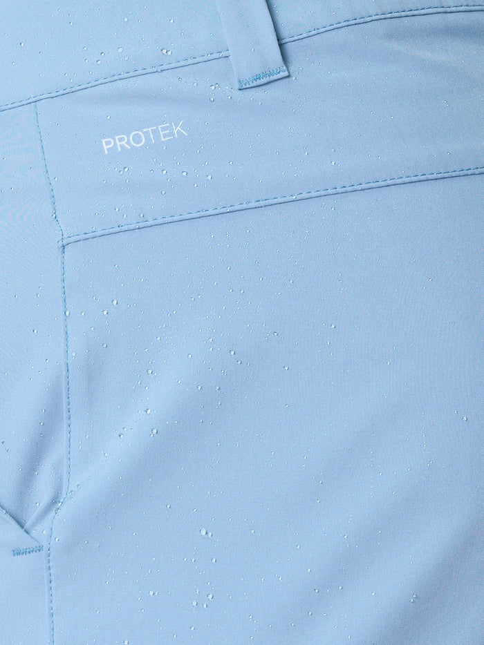 Close up of sky blue Castore golf shorts fabric with water droplets and ProTek branding near the belt loop