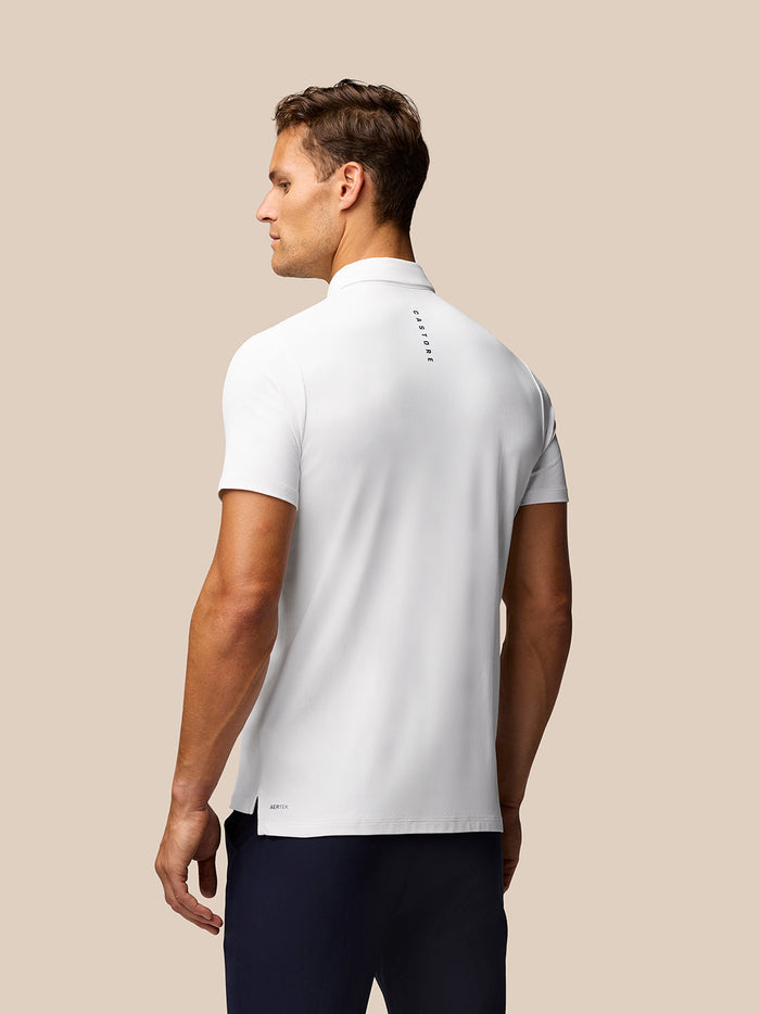 Back view of male model in white Golf Club Essential Polo showing Castore branding along the upper back.