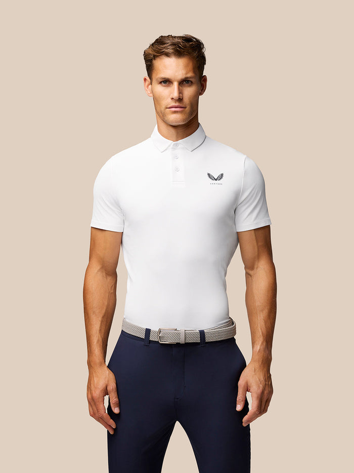 Front three-quarter view of male model wearing white Golf Club Essential Polo with Castore chest logo and three-button placket.