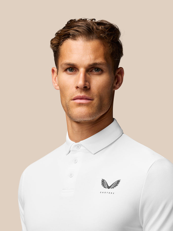 Close-up of white polo chest area showing Castore emblem on left chest.