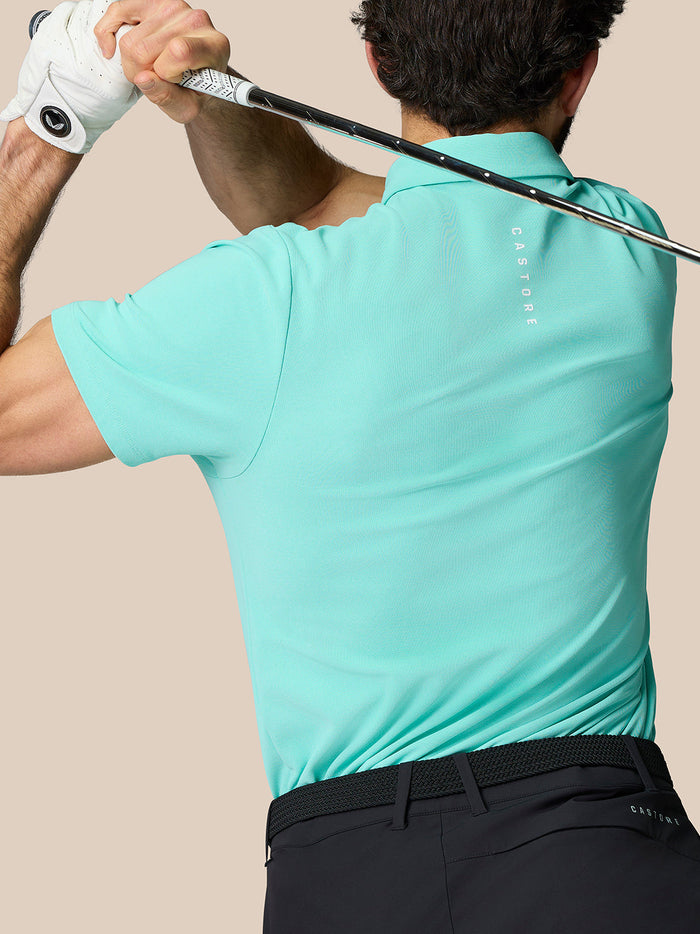Back view of a man in a light aqua golf polo showing Castore branding running down the back.