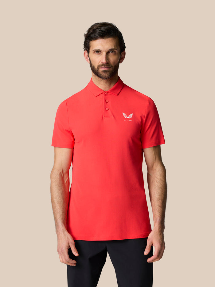 Male model in poppy red Golf Club Essential Polo with polo collar and Castore branding on chest