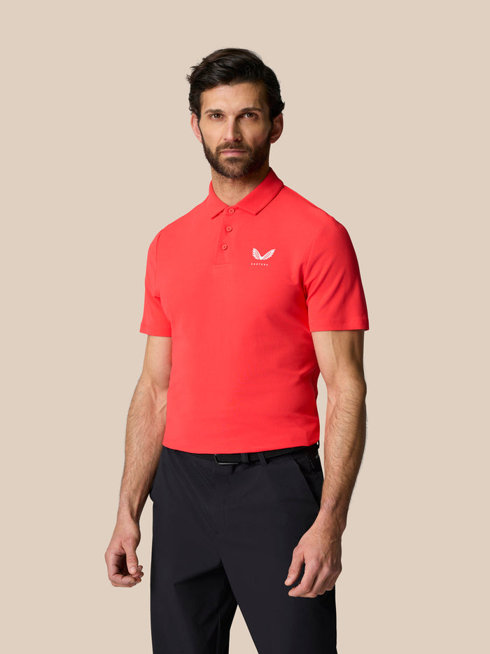 Male model wearing red Golf Club Essential Polo with white Castore logo on left chest.