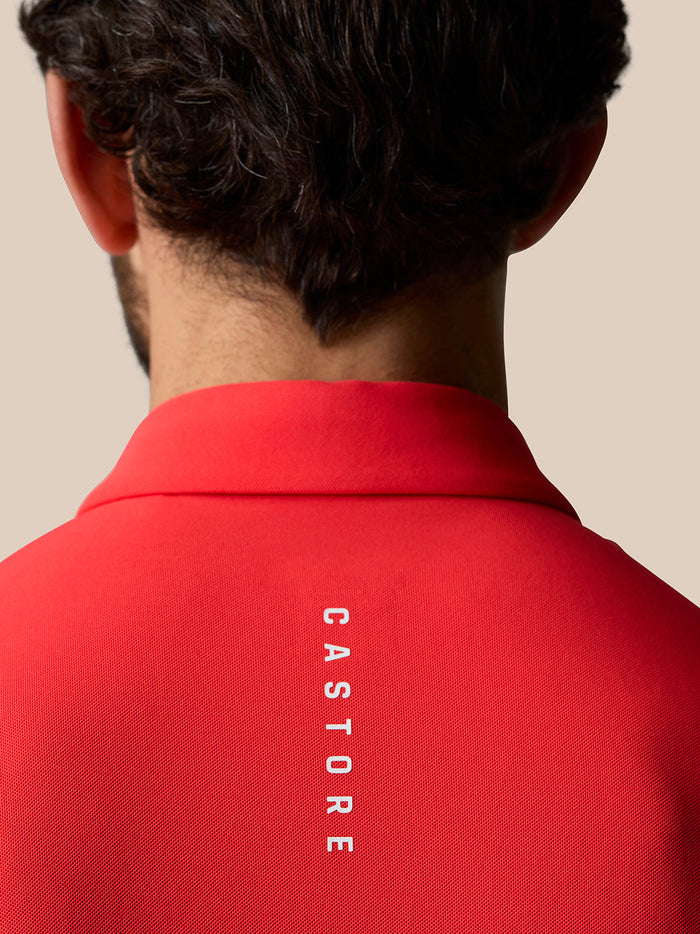 Back view of red Castore polo with white branding along the upper back.