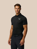 Male model wearing black Pinnacle Pique Stripe Polo with subtle stripes and Castore logo on the chest
