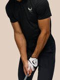 Golfer wearing Golf Pinnacle Pique Stripe Polo in black alloy while gripping a golf club