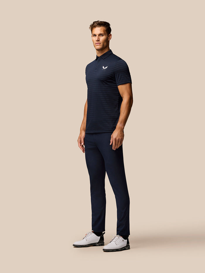 Male model wearing navy Pinnacle Pique Stripe Polo with striped pattern and Castore logo on left chest