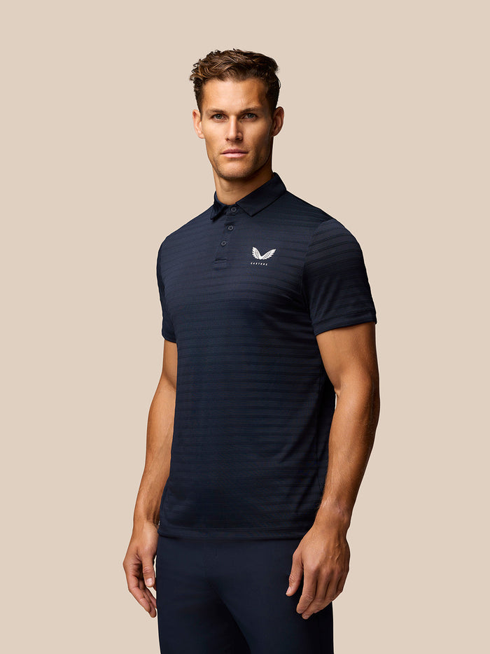 Man in navy Pinnacle Pique Stripe Polo with subtle stripes posing in front view showing Castore logo on chest
