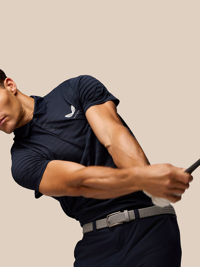 Male model in navy Pinnacle Pique Stripe Polo with subtle stripes and Castore branding on left chest during swing