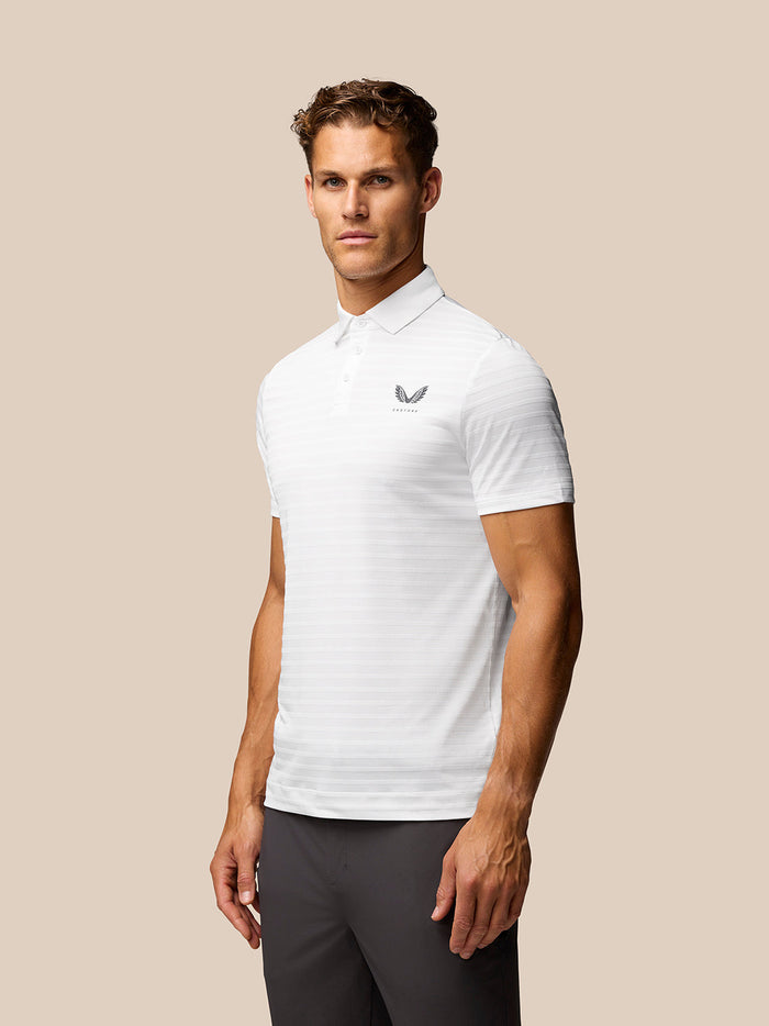 Male model wearing Golf Pinnacle Pique Stripe Polo in white with subtle stripes and Castore logo on chest.