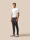 Male model in a white textured polo with stripes and gray trousers, posed in profile.