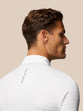 Back view of a male model wearing a white textured polo with stripes and Castore branding along the upper back.