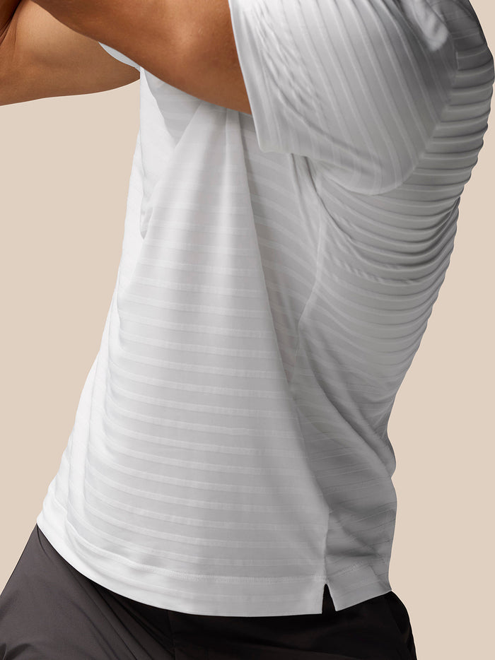 Close-up of white textured pique stripe polo fabric with a side hem split detail.