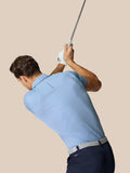 Male model in sky blue Engineered Knit Polo back view with Castore logo on upper back holding a golf club.