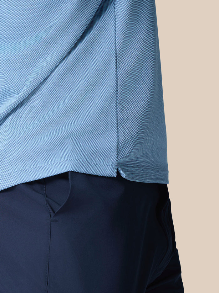 Close-up of light blue engineered knit fabric showing texture and side hem of Golf Pinnacle Polo