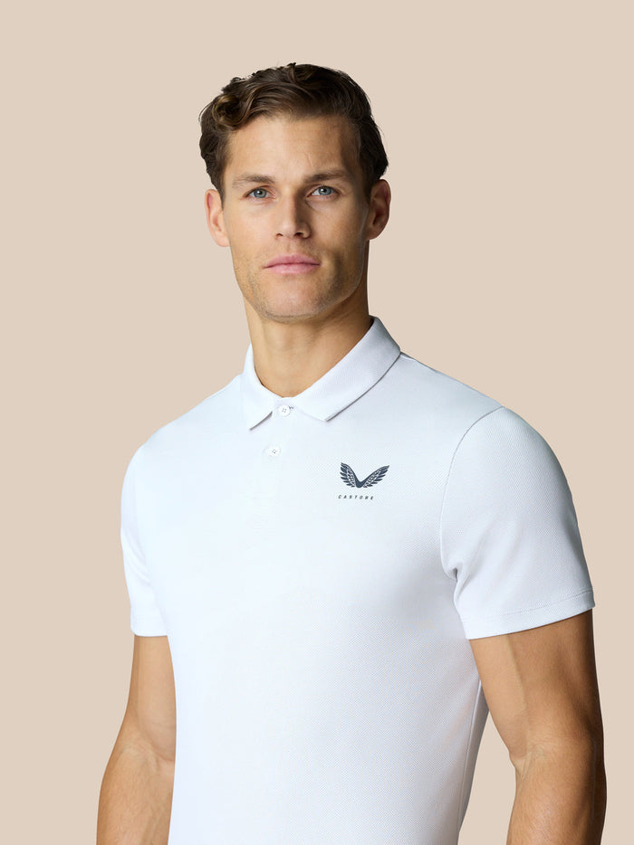 Male model wearing white Golf Pinnacle Polo with a pointed collar and Castore logo on the chest