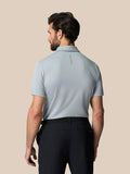 Back view of male model wearing a light grey Engineered Knit Polo with Castore branding along the upper back.