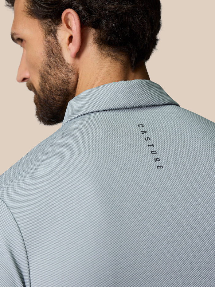 Back view of a mid grey polo showing CASTORE branding along the upper back.