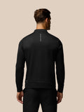 Back view of a man in a black long sleeve top with vertical CASTORE branding on the upper back
