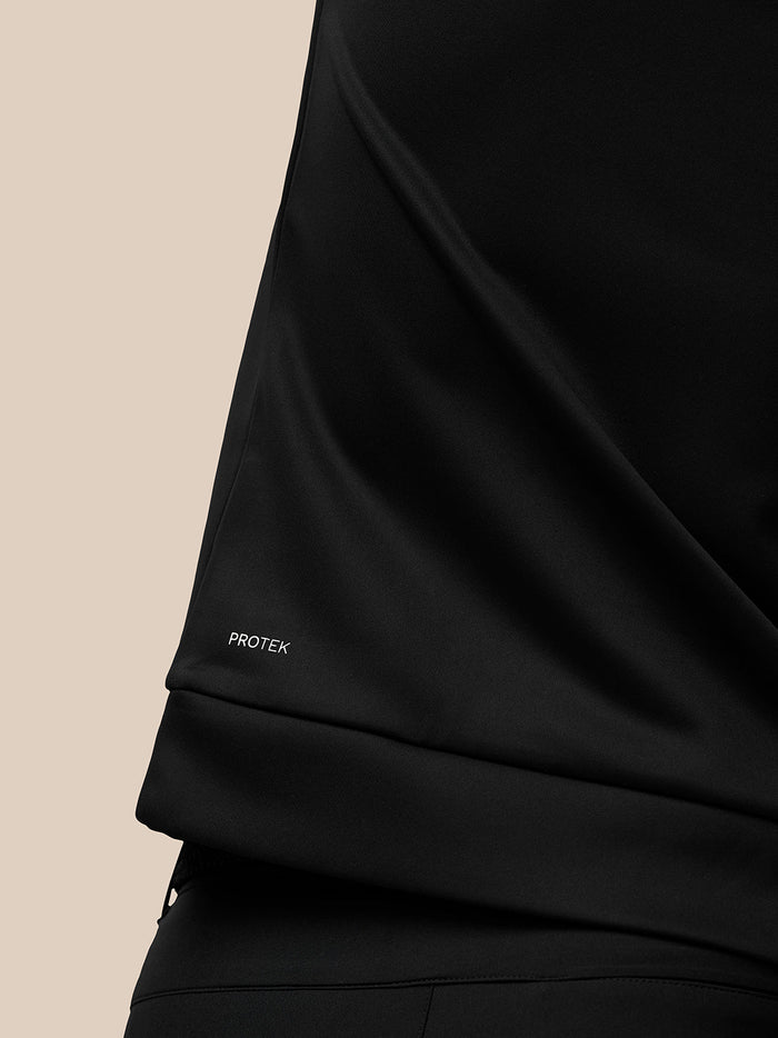 Close up of the sleeve cuff showing PROTEK branding on the black Golf Club Classic top.