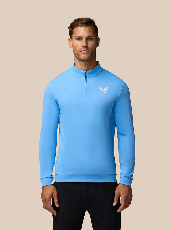 Man wearing light blue Golf Club Classic 1/4 Zip Top with stand collar and left chest logo.