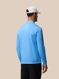 Back view of a man wearing a light blue Golf Club Classic quarter zip top against a beige backdrop