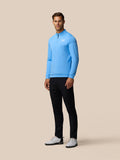 Full-length shot of a man in a light blue Golf Club Classic quarter zip top with front zipper left chest logo and white cap against a beige backdrop