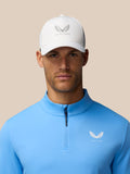 Golfer in white cap and blue quarter zip top with Castore logo on the chest.