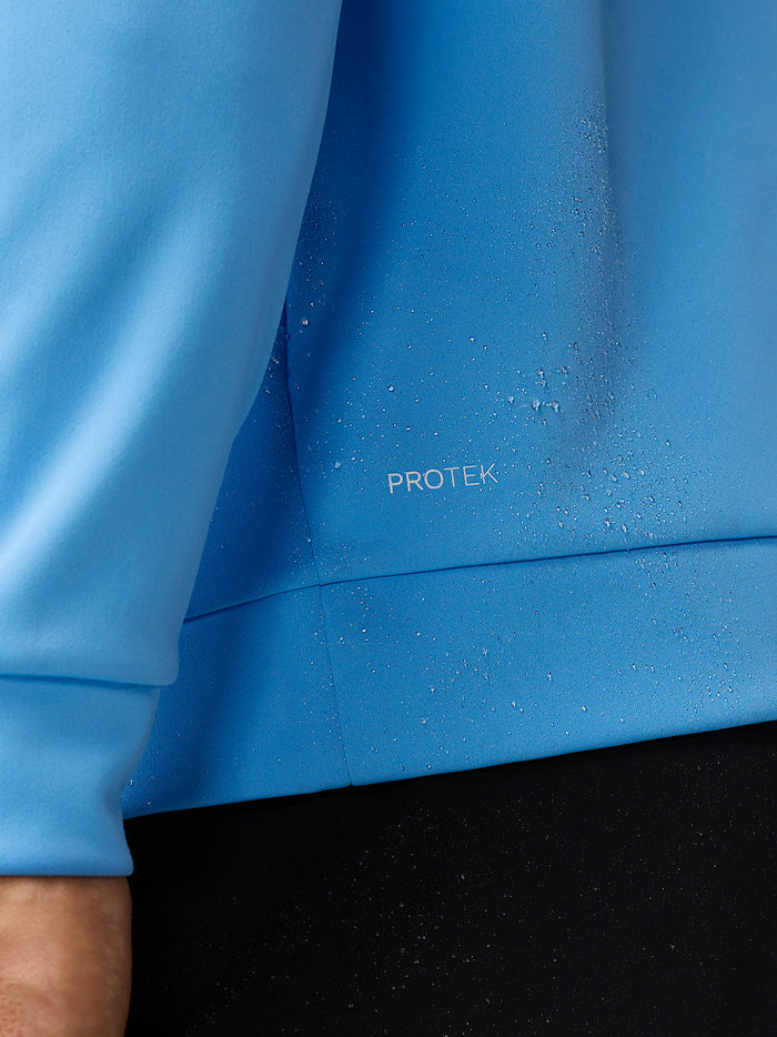 Man in light blue Golf Club Classic quarter zip top with stand-up collar front zipper white golf shoes and black trousers