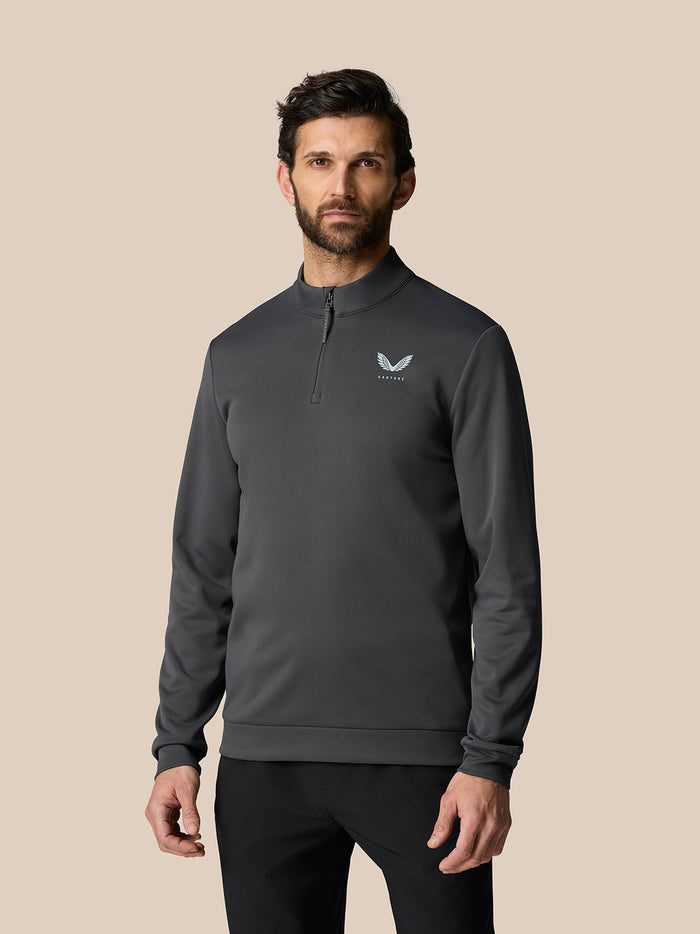 Man wearing gunmetal golf club classic quarter zip top with stand collar and Castore logo on the chest
