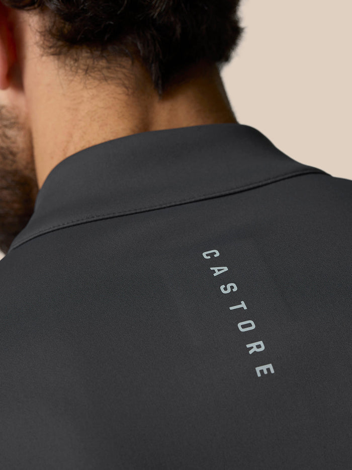 Close-up of a gunmetal golf quarter zip top seen from the back with Castore branding along the upper back.