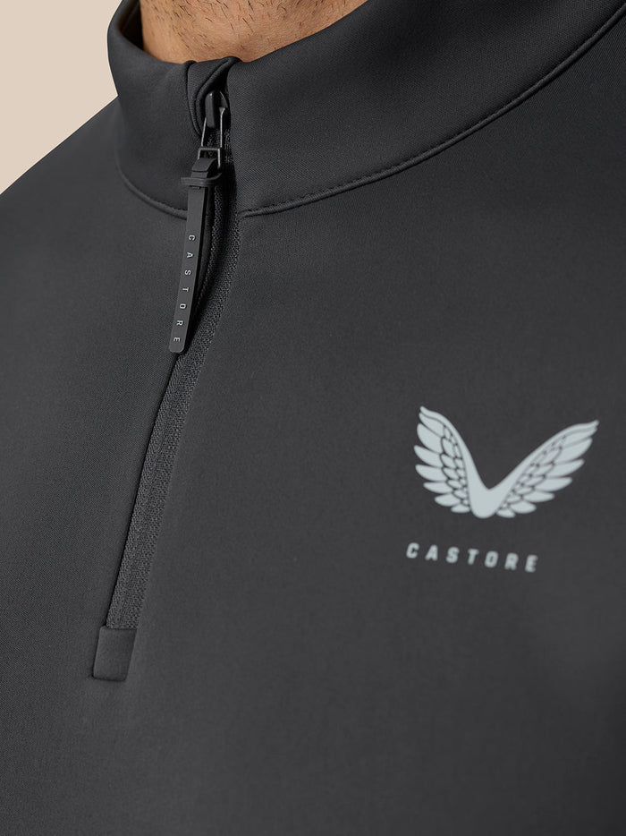 Close-up of the front zip neckline on a dark golf top with Castore logo on the left chest.