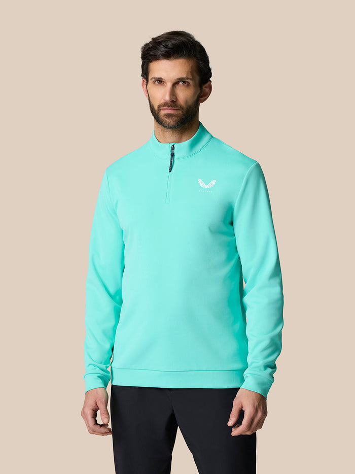 Male model wearing light aqua Golf Club Classic Quarter Zip Top with stand collar and chest Castore logo