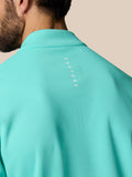 Back view of light aqua golf quarter zip top featuring vertical Castore branding along the upper back.
